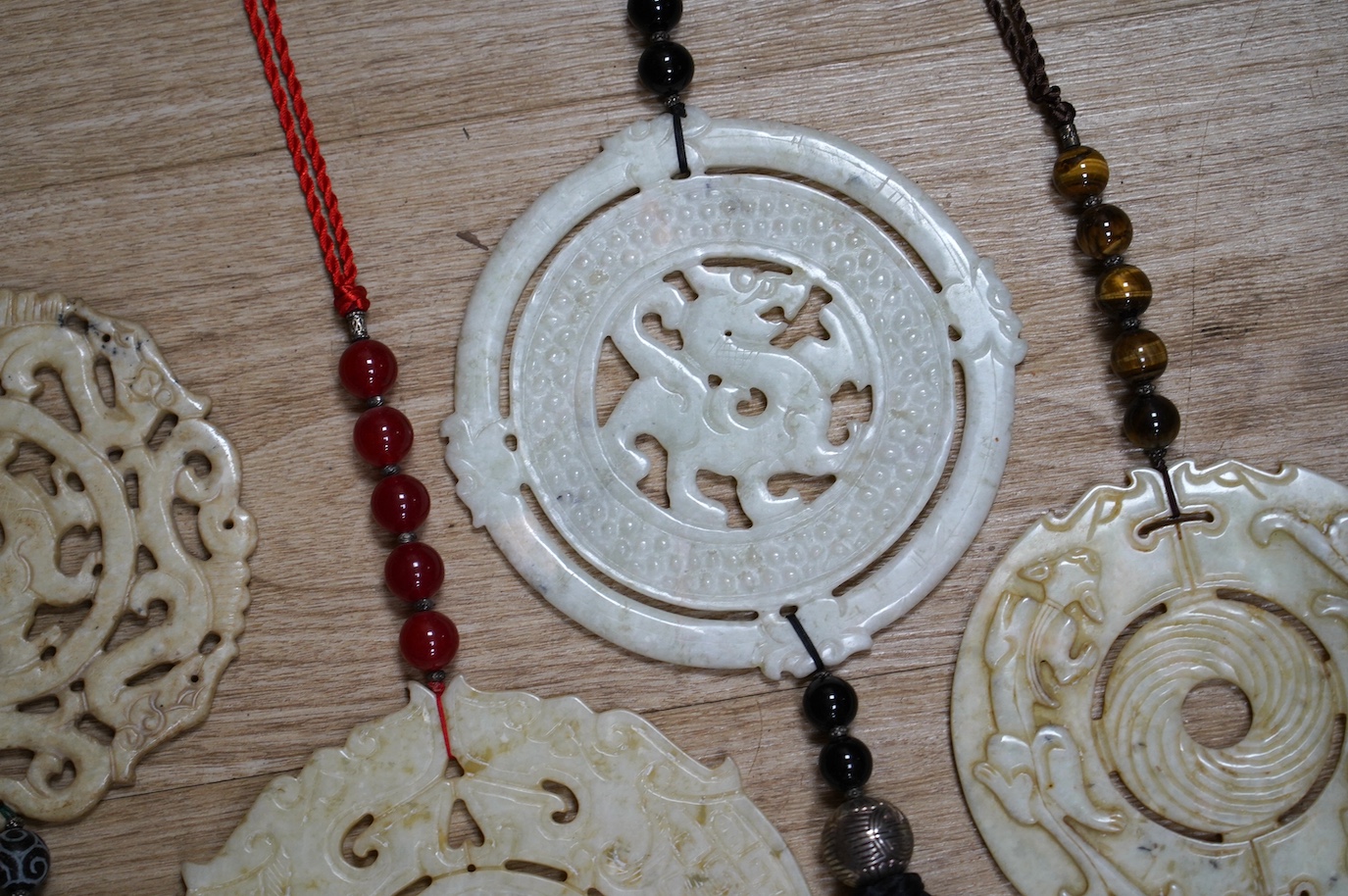 Four large Chinese carved bowenite jade discs, largest diameter 19cm, with tassel and bead wall hangings. Condition - fair to good